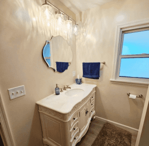 Elegant bathroom vanity with mirror, lighting, and blue towels in a cozy space.