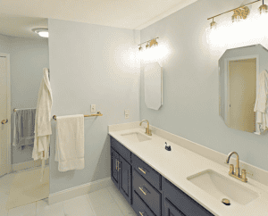 Bright bathroom with dual sinks and navy blue cabinetry.