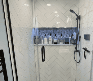 Modern shower with built-in niche featuring blue mosaic tiles and sleek fixtures.