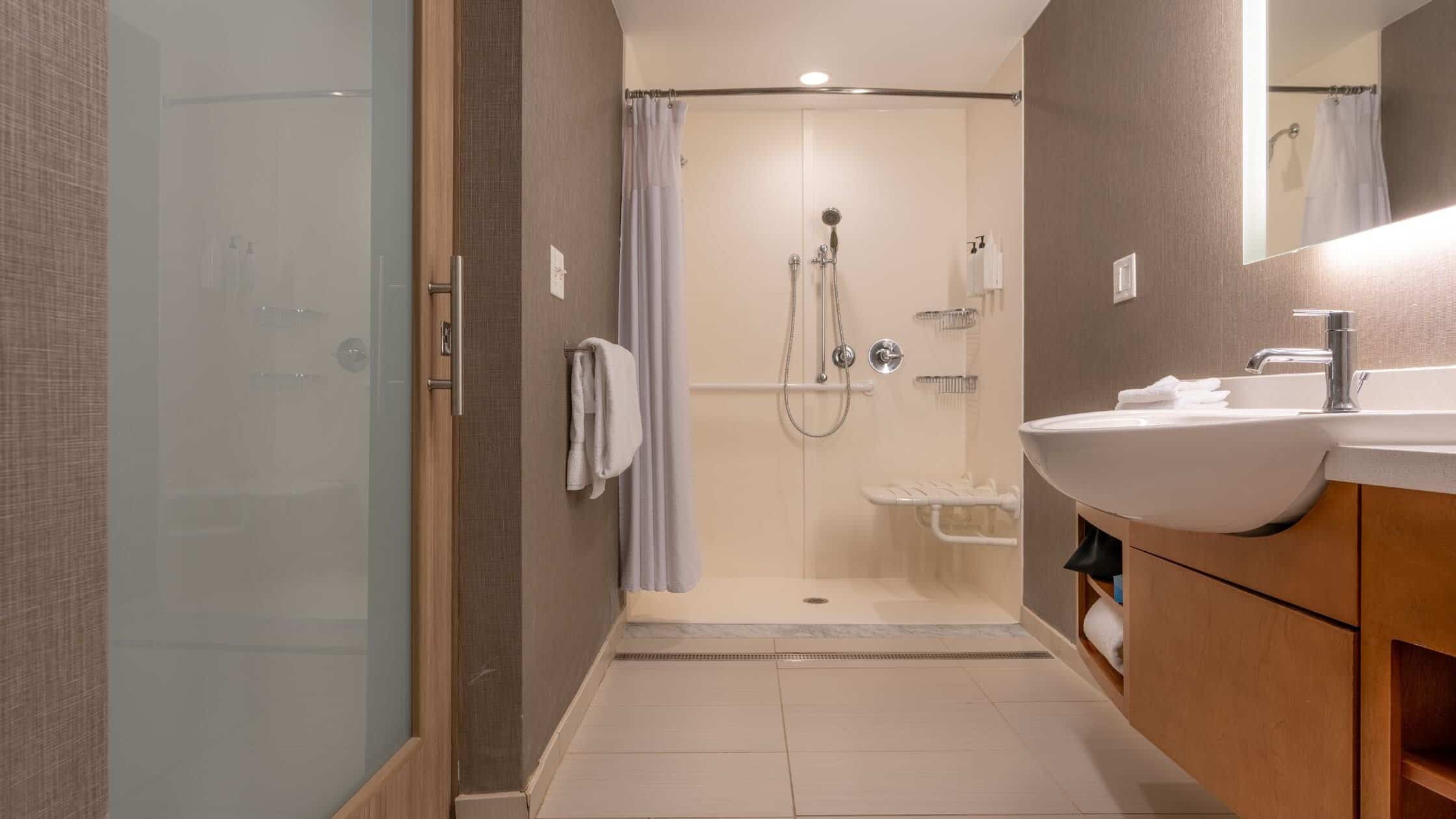Modern Bathroom Accessible shower with glass door and seating.