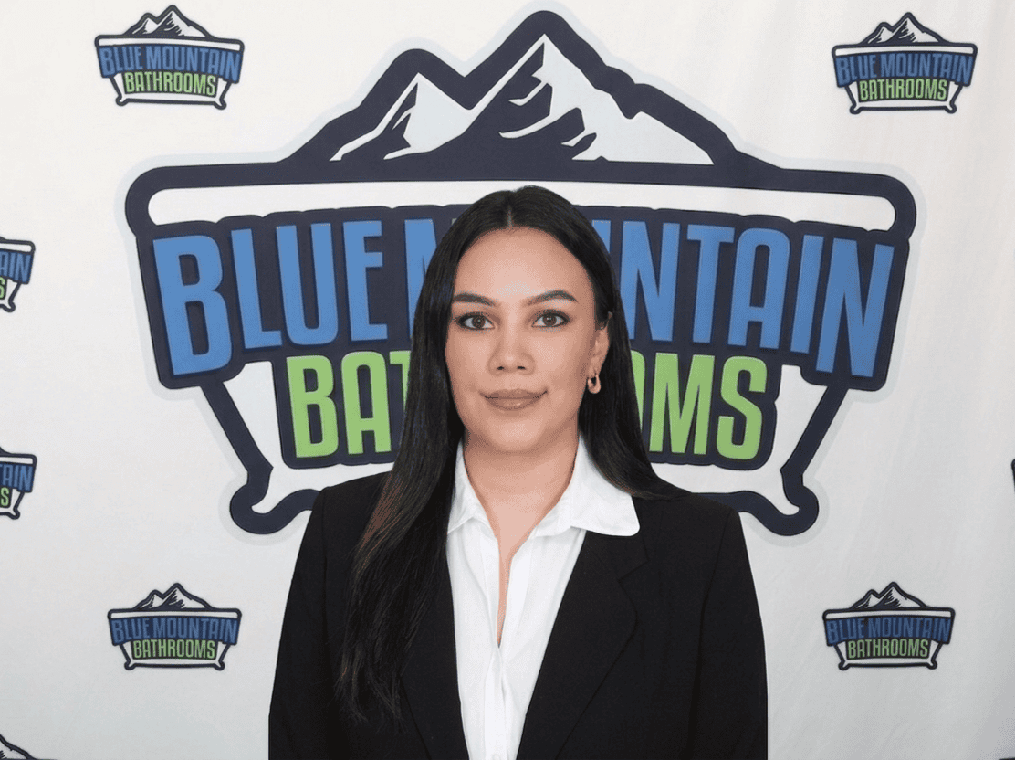 Professional woman standing in front of Blue Mountain Bathrooms logo backdrop.