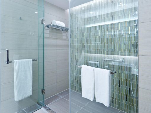Modern bathroom shower with glass enclosure and green mosaic tile accent wall.