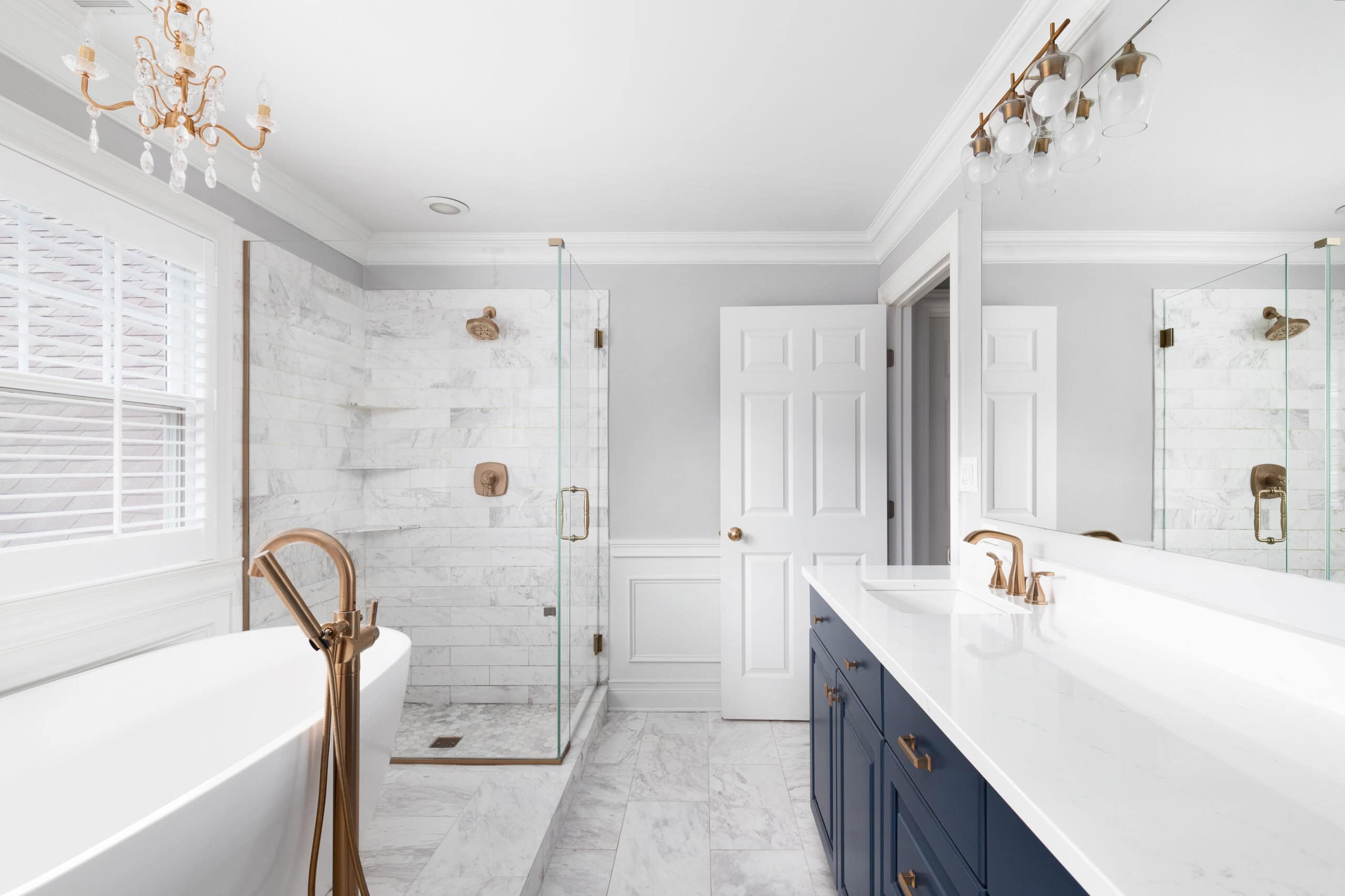 Modern bathroom with white and navy blue decor, bathtub, and glass shower enclosure.